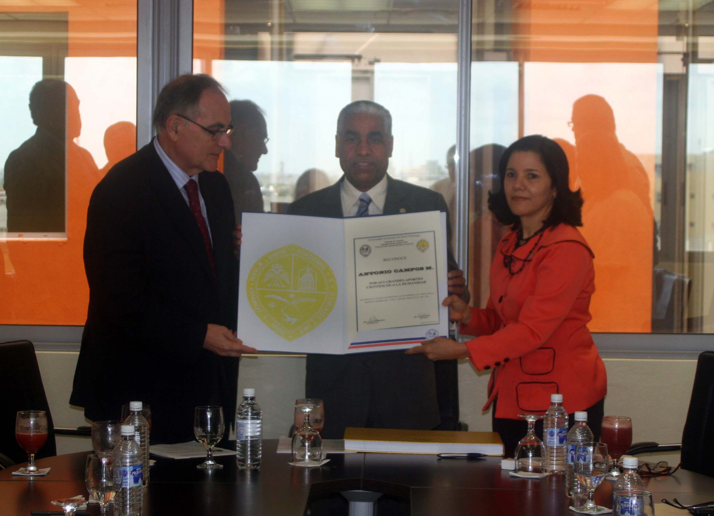 Doctor Campos Muñoz recibiendo reconocimiento de manos del decano y la vice-decana FCS.